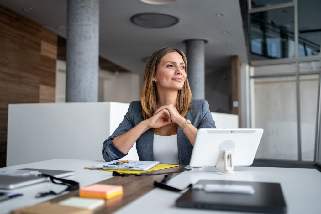 Businesswoman smiling and looking away while sitting at desk