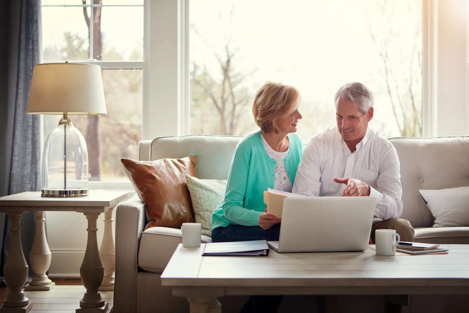 Couple reviewing household bills and financial documents on a laptop at home