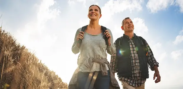 Retired couple hiking together on a sunny hillside